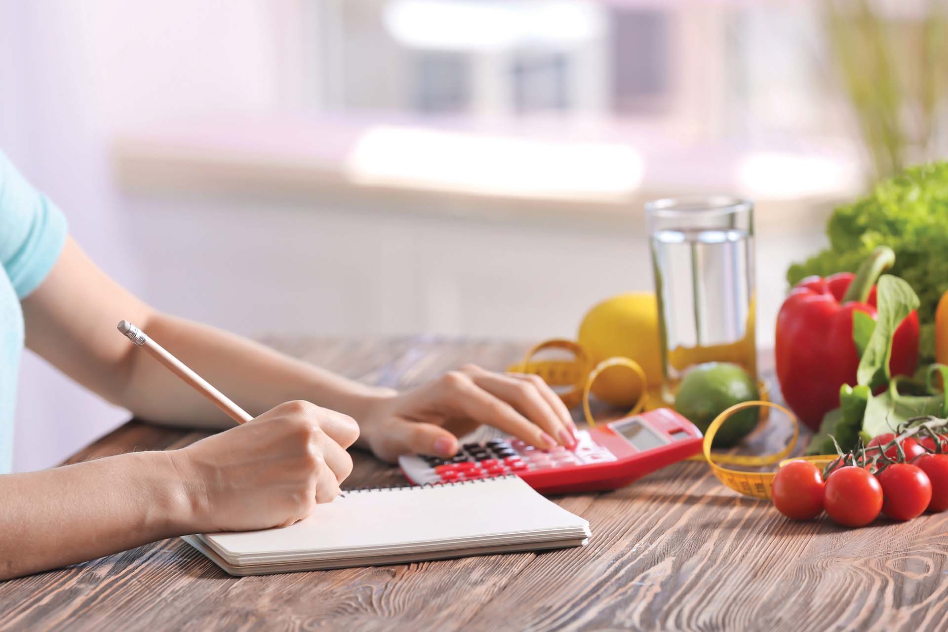 Young woman calculating calories at table. Weight loss concept