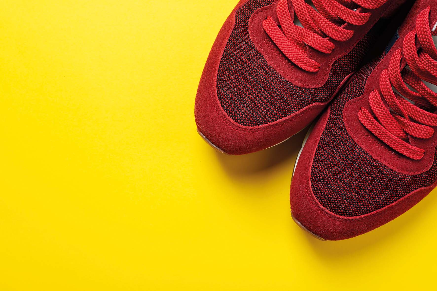 New red sneakers on a yellow background. space for text. Pair of sport shoes.